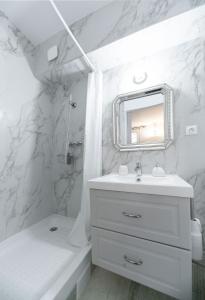 une salle de bain blanche avec un lavabo et un miroir dans l'établissement Résidence Aristide Briand - Appartements en Centre Ville, à Vichy