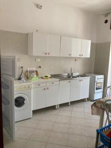 cocina con armarios blancos, lavadora y secadora en Tizi Apartments en Maiori