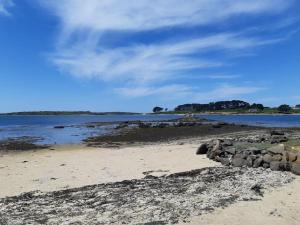 uma praia com rochas e água e um céu nublado em Maison bord de mer em Plouguerneau