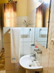 a bathroom with a sink and a mirror at EAR KEN BARHAM GUESTHOUSE in Rwumba
