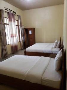 a hotel room with two beds and two windows at EAR KEN BARHAM GUESTHOUSE in Rwumba