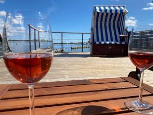 two glasses of wine sitting on a wooden table at Hausboot Bali in Fehmarn
