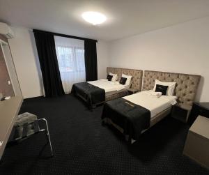 a hotel room with two beds and a window at Renato HOUSE in Târgu Jiu