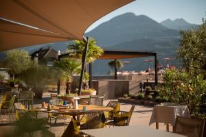 a patio with tables and chairs with mountains in the background at Hotel Muchele in Merano