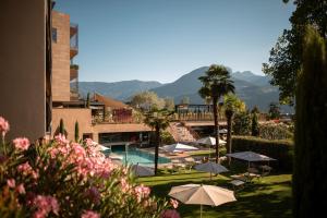 un complejo con piscina, sombrillas y montañas en Hotel Muchele en Merano