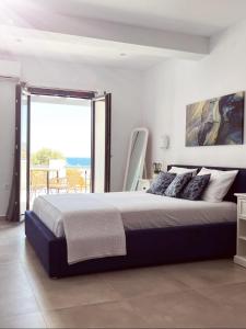 een slaapkamer met een groot bed en een groot raam bij All Blue Suites in Ambelas