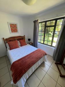 a bedroom with a bed and a large window at Getaway cottage in Lovemore Park