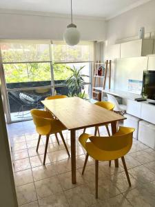 cocina con mesa de madera y sillas amarillas en 2 ambientes cerca de la playa, en el centro en Mar del Plata