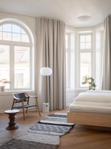 a bedroom with a bed and a chair and windows at Hotel 1904 in Ålesund