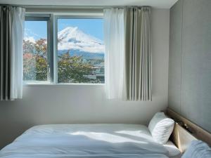 a bedroom with a bed and a window with a snow covered mountain at Megu fuji 2021 - Vacation STAY 74532v in Fujiyoshida