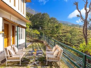 a balcony with chairs and a table with a view at Rakkh Resort in Pālampur