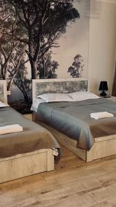 two beds in a room with trees on the wall at Rosheli Apartments in Manglisi