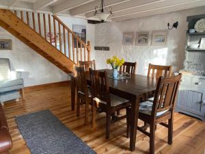 uma sala de jantar com uma mesa de madeira e cadeiras em Dog friendly cottage with woodland & lake em Helston