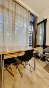 een houten tafel met twee stoelen voor een raam bij Rosheli Apartments in Manglisi