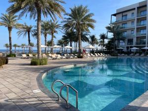 a swimming pool at a resort with palm trees at Resort Address Beach Fujairah,3BRoom Resort Address Beach Fujairah,3BRoom in Fujairah