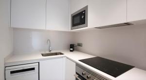 a white kitchen with a sink and a microwave at Loft vistes al mar 50 mts to Palamós Beach in Palamós
