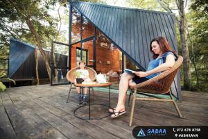 une femme assise sur une chaise sur une terrasse avec un enfant dans l'établissement Gabaa Resort & Spa - Habarana, à Habarana