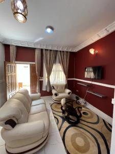 Appartement New Stading YAOUNDE - MIMBOMAN MAETURE في ياوندي: غرفة معيشة مع أريكة بيضاء وكرسيين