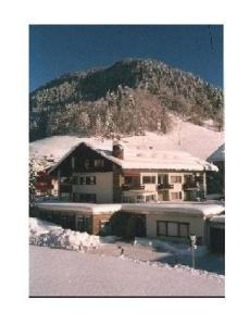 ein Haus im Schnee mit einem Berg im Hintergrund in der Unterkunft Sport Alpin Wohnung 1 in Oberstdorf