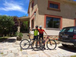 dos hombres parados junto a sus bicicletas delante de una casa en Casa Rural Las Tuyas en Segovia en Palazuelos de Eresma