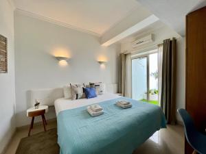 Albufeira Stylish by Homing في ألبوفيرا: غرفة نوم بسرير وبطانية زرقاء ونافذة