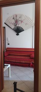 een kamer met een rode bank en een ventilator bij Casa Fiori di Arancio in Valledoria