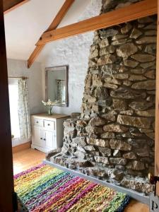 uma sala de estar com uma parede de pedra e um tapete em Dog friendly cottage with woodland & lake em Helston