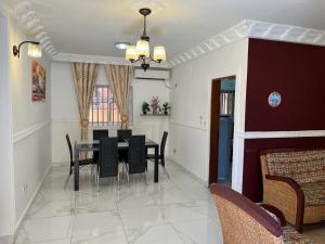 a dining room with a table and black chairs at Appartement New Stading YAOUNDE - MIMBOMAN MAETURE in Yaoundé