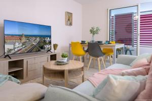 a living room with a tv and a table with yellow chairs at City Cocoon T2 rénové proche centre Saint Denis in Saint-Denis
