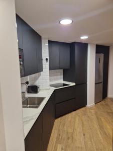 a kitchen with black cabinets and a wooden floor at Brand New Appartment very cosy and awesome display close to the ski slope! private parking in Sierra Nevada