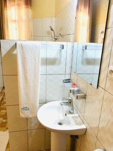 a bathroom with a sink and a mirror at EAR KEN BARHAM GUESTHOUSE in Rwumba