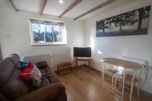 uma sala de estar com um sofá, uma mesa e uma televisão em Rose Hideaway - Forest of Dean Cosy Cabin Retreat em Yorkley
