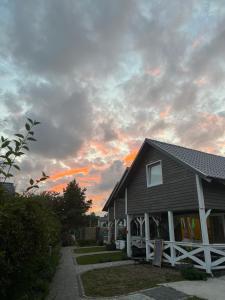 dom z zachodem słońca na niebie za nim w obiekcie Lawendowe domki w Karwii