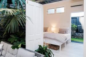 Cette chambre comprend un lit et une terrasse couverte ornée de plantes. dans l'établissement Driftwood Beach House, à Kiama