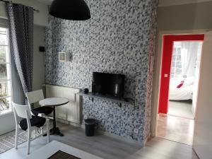 een woonkamer met een tafel en een tv aan de muur bij LESSENCIEL in Tournay
