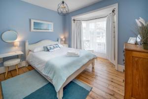a blue bedroom with a bed and a window at Blue Winds and Waves in Cowes
