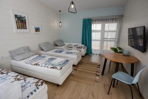 a living room with three beds and a table at Halfarock Vízi-Erdei Apartmanház in Levelek