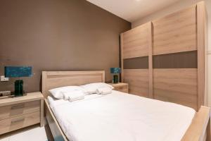 una camera da letto con un grande letto bianco con due cuscini di BLUEMARINE Suite-Hosted by Sweetstay a San Giuliano