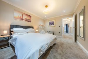 ein Schlafzimmer mit einem großen weißen Bett und einem Flur in der Unterkunft Brand New London Luxury House - Sleeps 8 in London