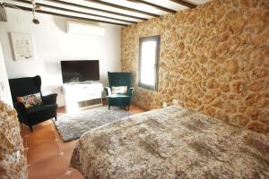 1 dormitorio con 1 cama, 2 sillas y TV en La Cueva, en Altea