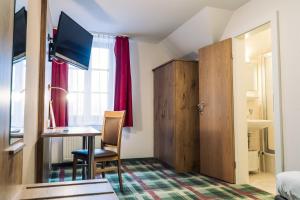 Zimmer mit einem Schreibtisch, einem Tisch und einem Fenster in der Unterkunft Gasthaus Kampenwand Bernau in Bernau am Chiemsee