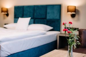 1 dormitorio con 1 cama y un jarrón con flores sobre una mesa en Ruben Hotel Zielona Góra en Zielona Góra