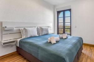 - une chambre avec un grand lit et 2 serviettes dans l'établissement Quinta dos Arcos 2BR w/ AC & Pool by LovelyStay, à Alvor
