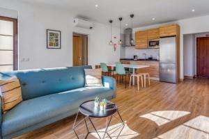 Il comprend un salon avec un canapé bleu et une cuisine. dans l'établissement Quinta dos Arcos 2BR w/ AC & Pool by LovelyStay, à Alvor