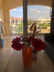 an orange vase with red flowers sitting on a table at Mazotos Panoramic Village in Mazotos