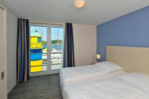 een slaapkamer met een bed en een raam met uitzicht bij Apartmenthaus Hafenspitze Ap 21, Blickrichtung Binnenhafen NordOffenes Meer - a72367 in Eckernförde