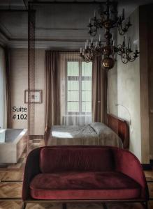 クラクフにあるホテル ポッド ロザのベッドルーム1室(ベッド1台、赤いソファ付)