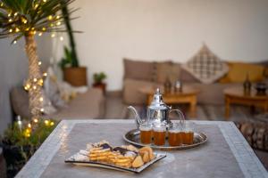 een tafel met een waterkoker en een bord eten bij Casa Janoub Morocco in Tamraght Ou Fella