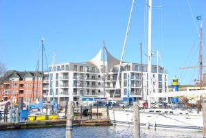 a boat docked in a marina with a large building at Apartmenthaus Hafenspitze Ap 42 "Segler", mit Sauna, Blickrichtung offene See - a72332 in Eckernförde