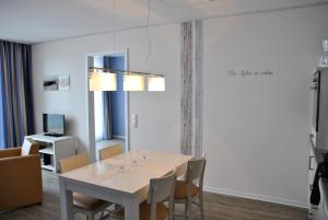 uma sala de jantar com mesa e cadeiras em Apartmenthaus Hafenspitze Ap 42 "Segler", mit Sauna, Blickrichtung offene See - a72332 em Eckernförde
